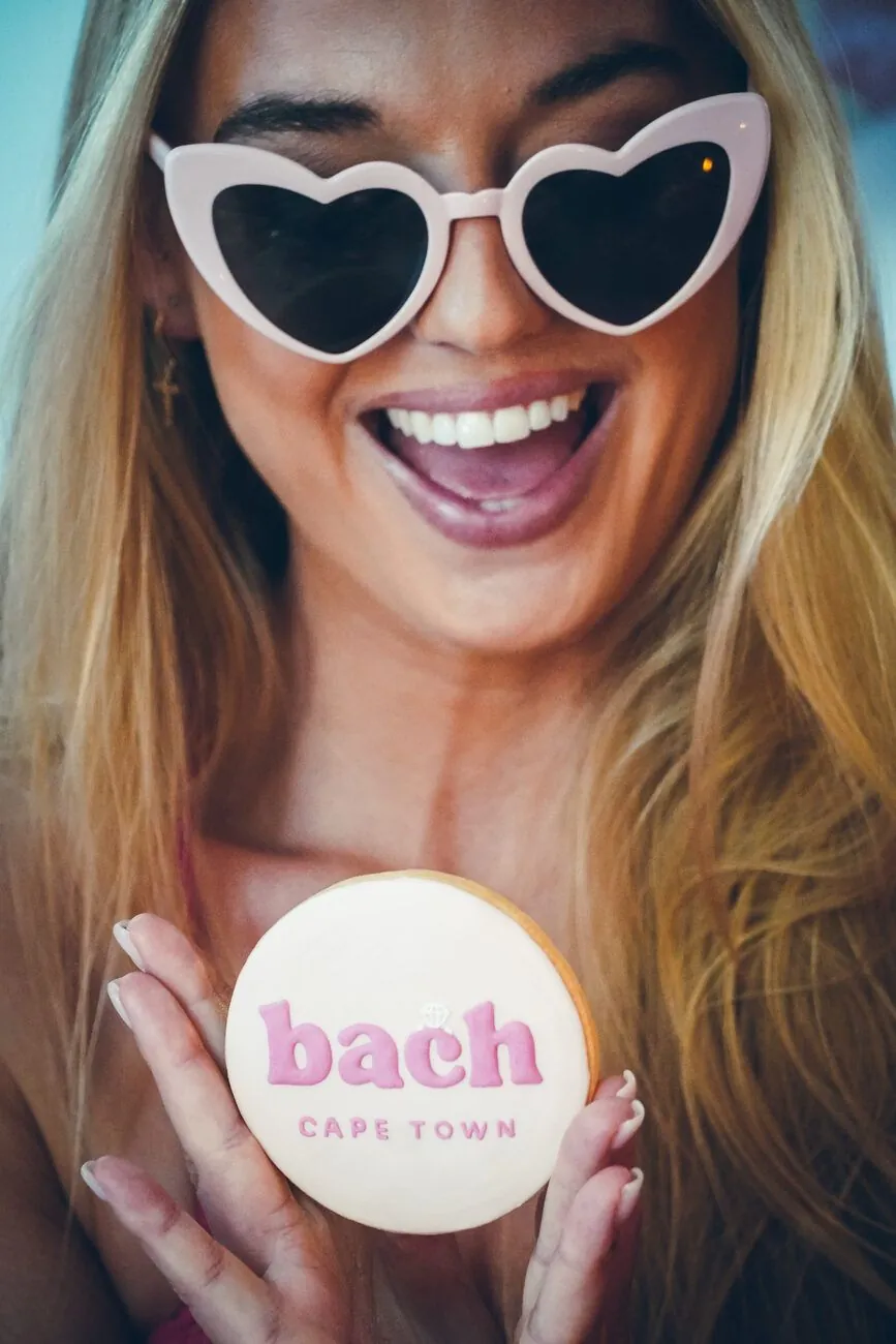 Guest in heart sunglasses holding a custom iced bach Cape Town cookie