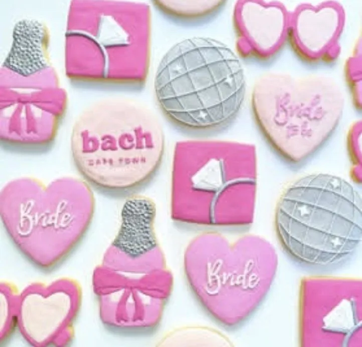 Flatlay of custom iced bach Cape Town bachelorette cookies in pink with disco balls, hearts and champagne bottles