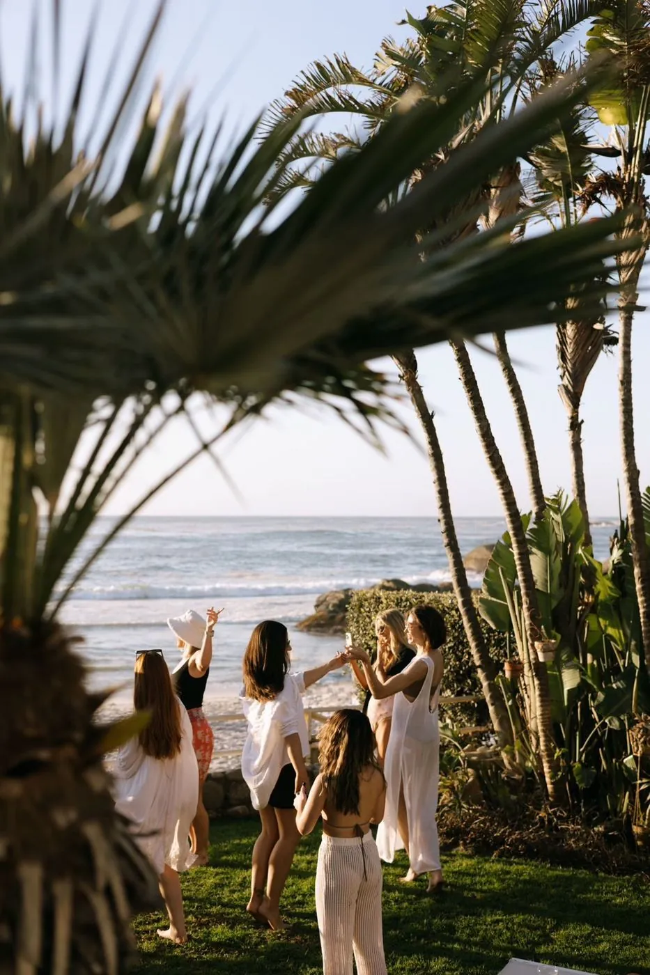 Bachelorette group toasting under palm trees beside the Atlantic at golden hour, Cape Town