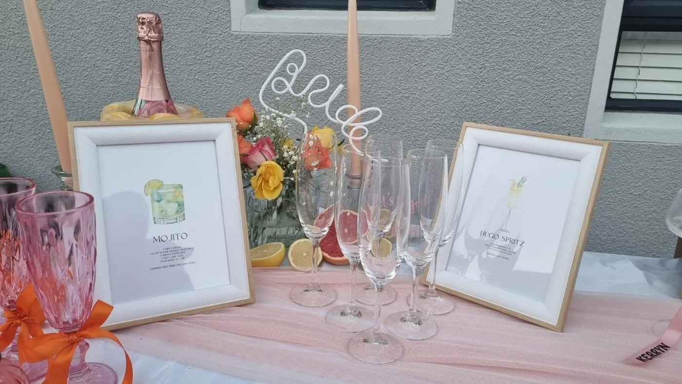 Styled cocktail bar with framed Mojito and Hugo Spritz recipe prints and a wire Bride sign