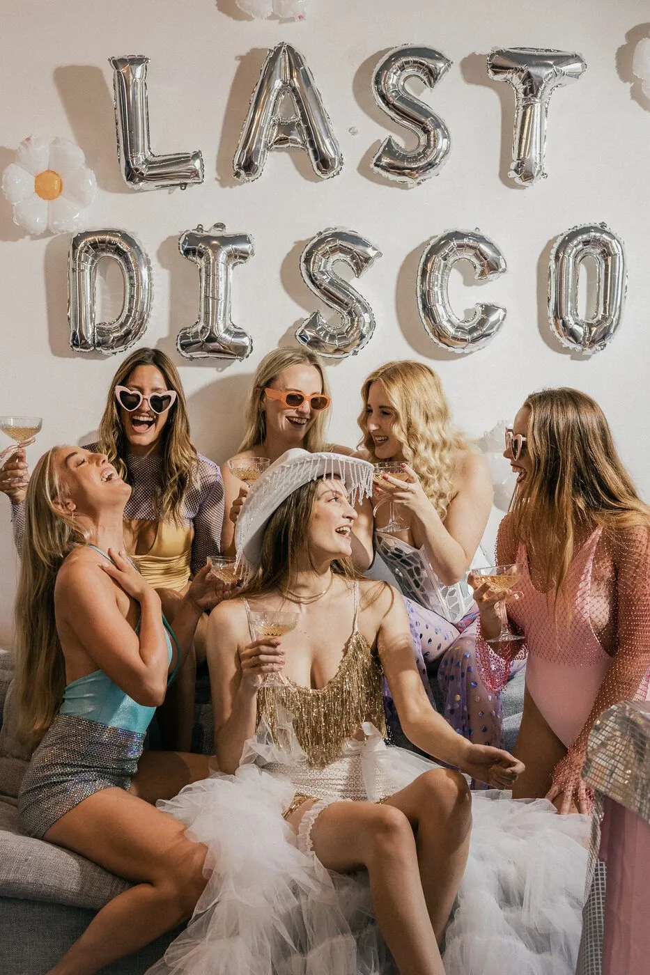 Bridal party in sparkle and coupes under a LAST DISCO backdrop