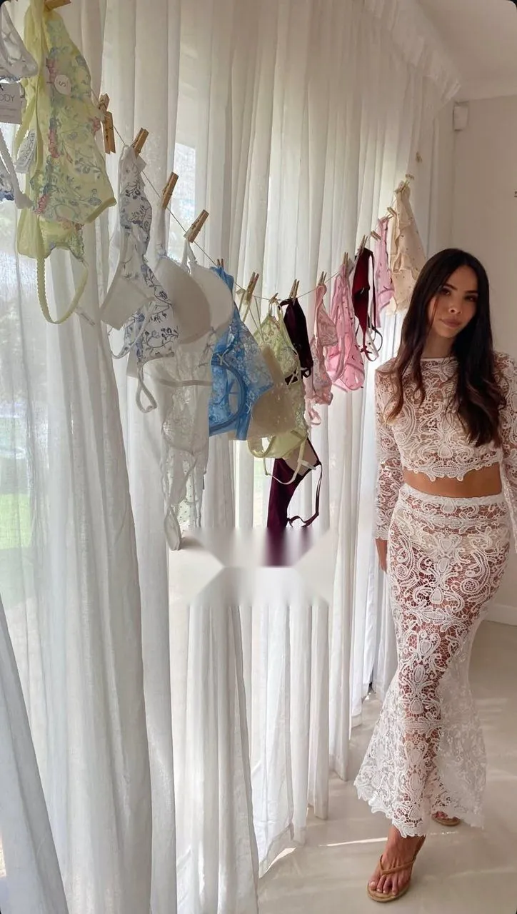 Bride to be in a white lace co-ord beside a styled lingerie-shower clothesline