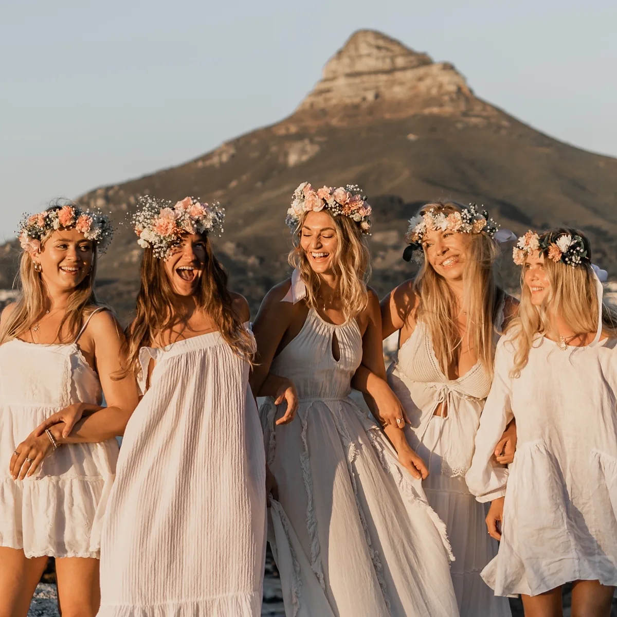 Bachelorette group in white dresses and flower crowns at golden hour below Lion’s Head, Cape Town