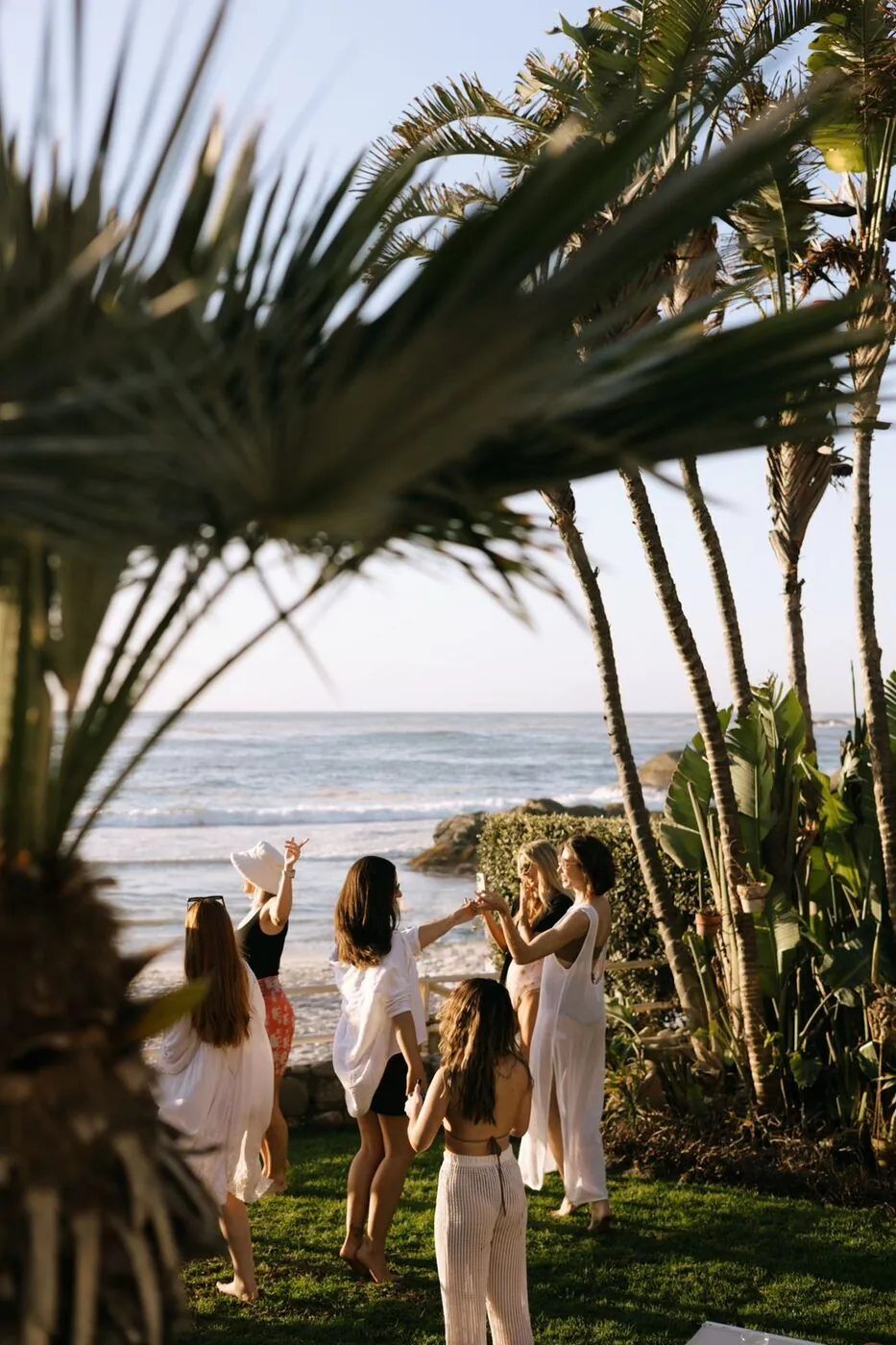 Bachelorette group celebrating by the ocean beneath palm trees in Cape Town