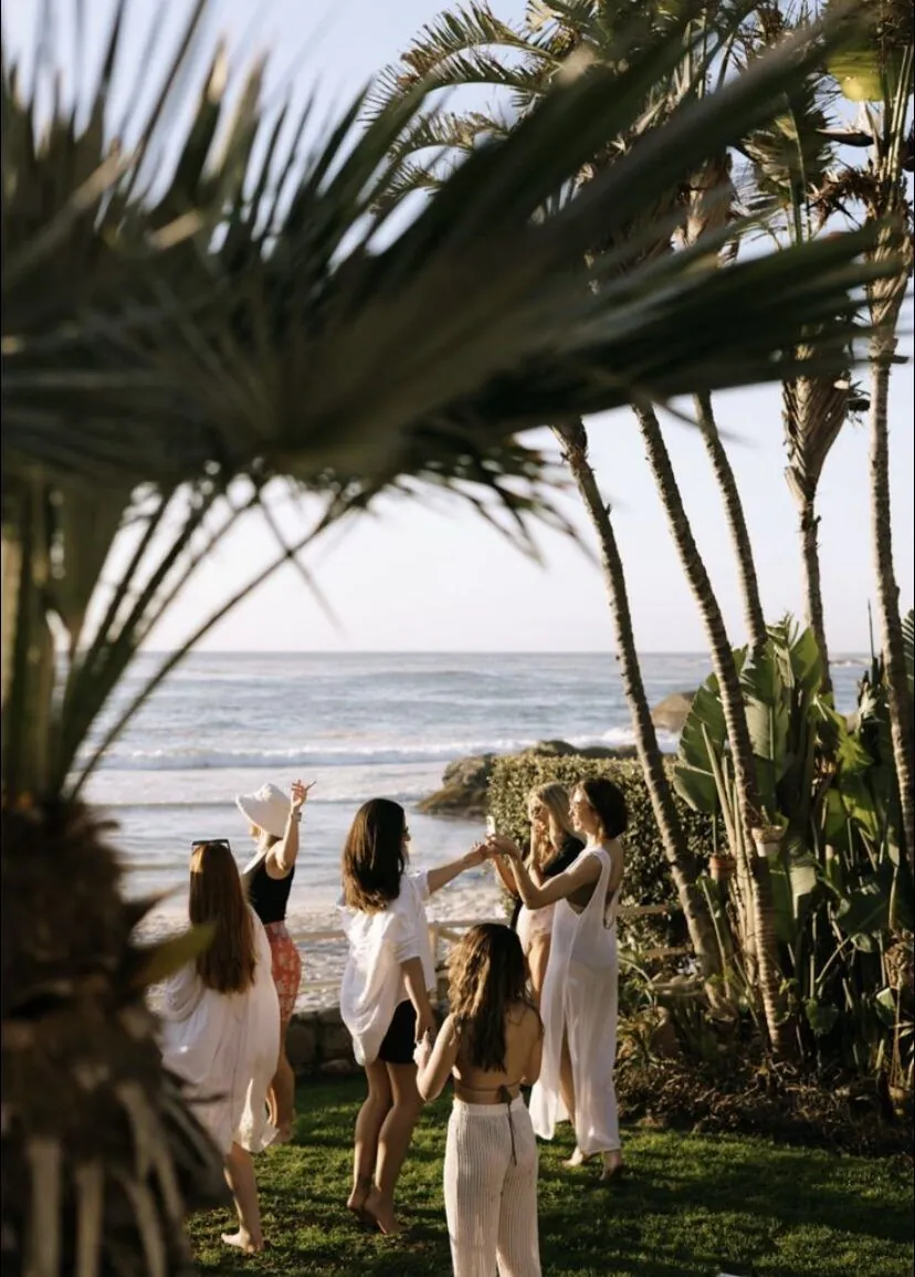 Friends raising a toast at golden hour by the Atlantic under palm trees, Cape Town