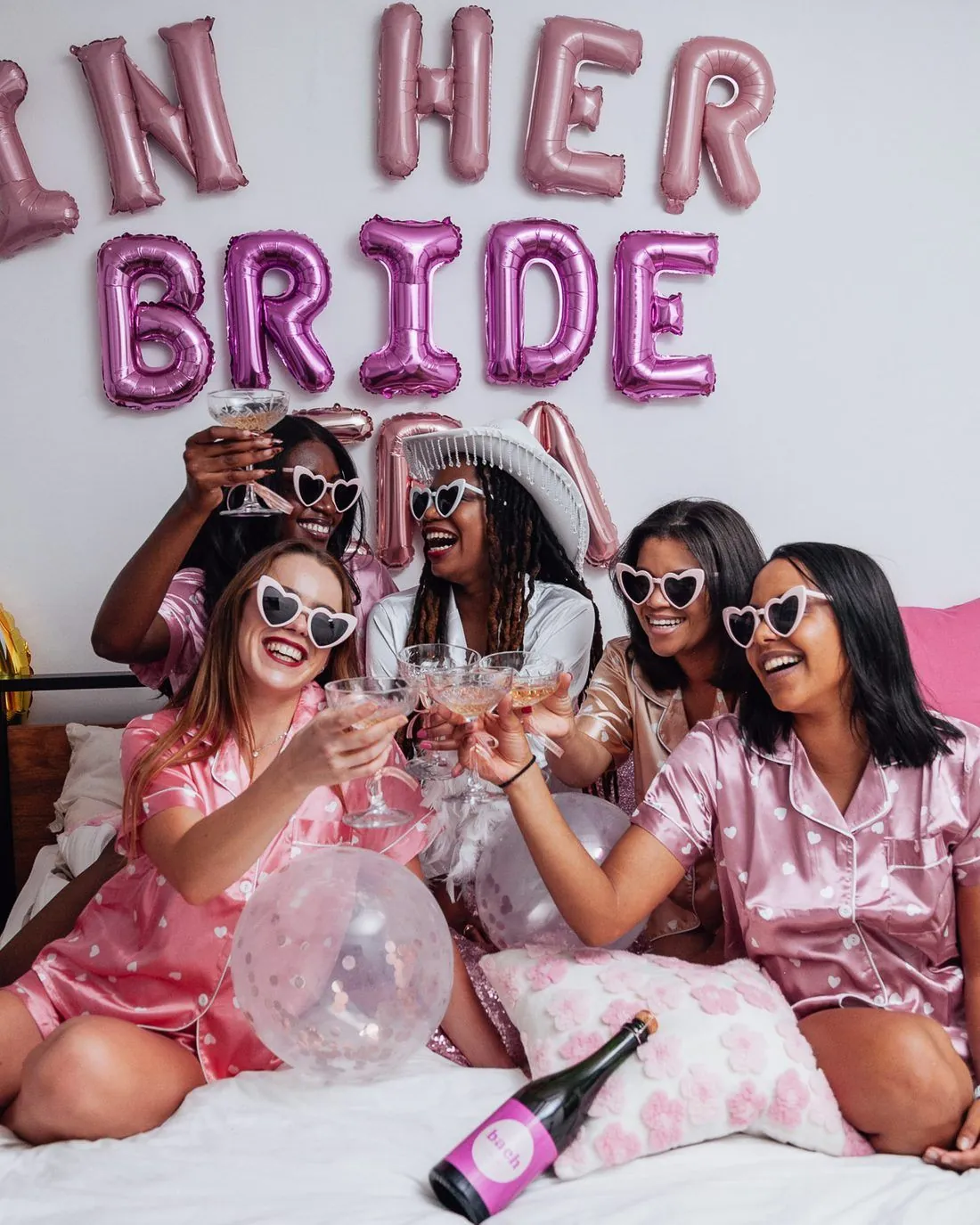 Bridal party in matching pink pyjamas toasting under In Her Bride Era balloons at a bachelorette, Cape Town