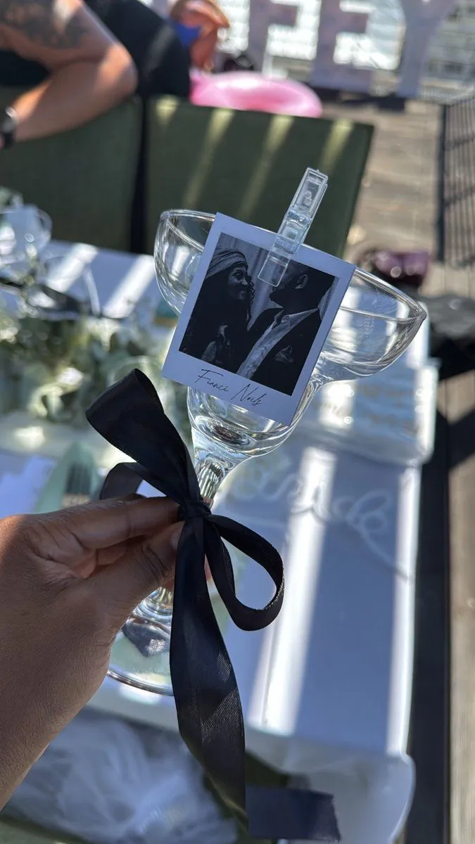 Coupe glass place setting with a black-and-white photo place card and black ribbon bow at a picnic