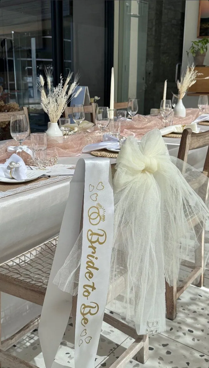 Bride to Be sash and ivory tulle bow styled on a chair beside an elegant tablescape with pampas